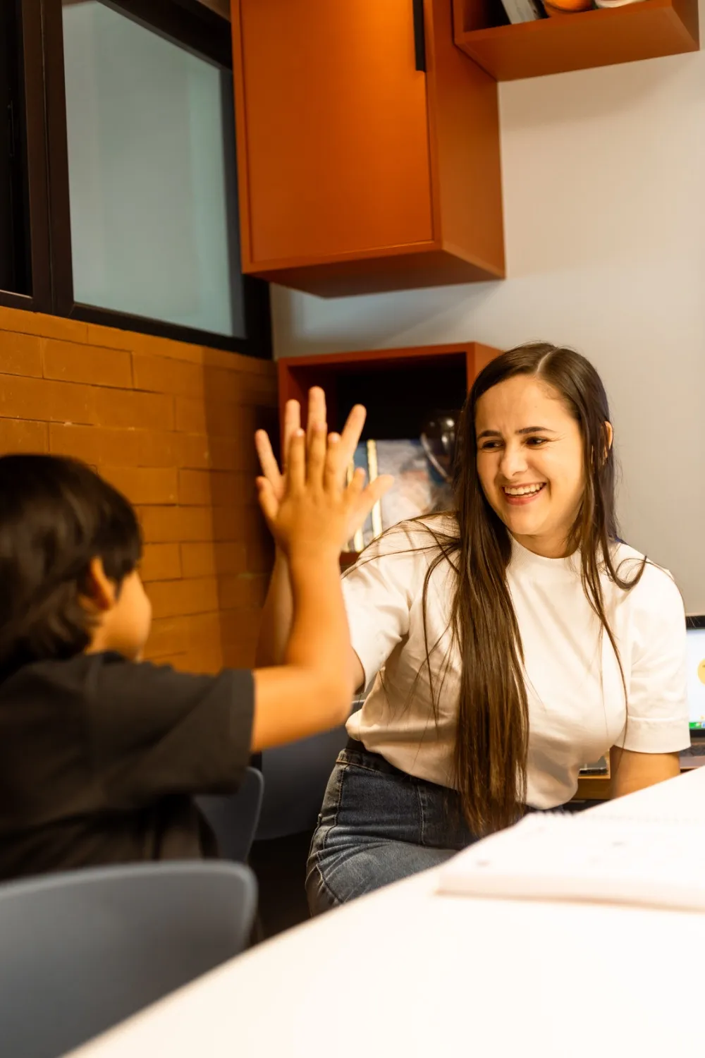 Professora e aluno trocando um high five em sala